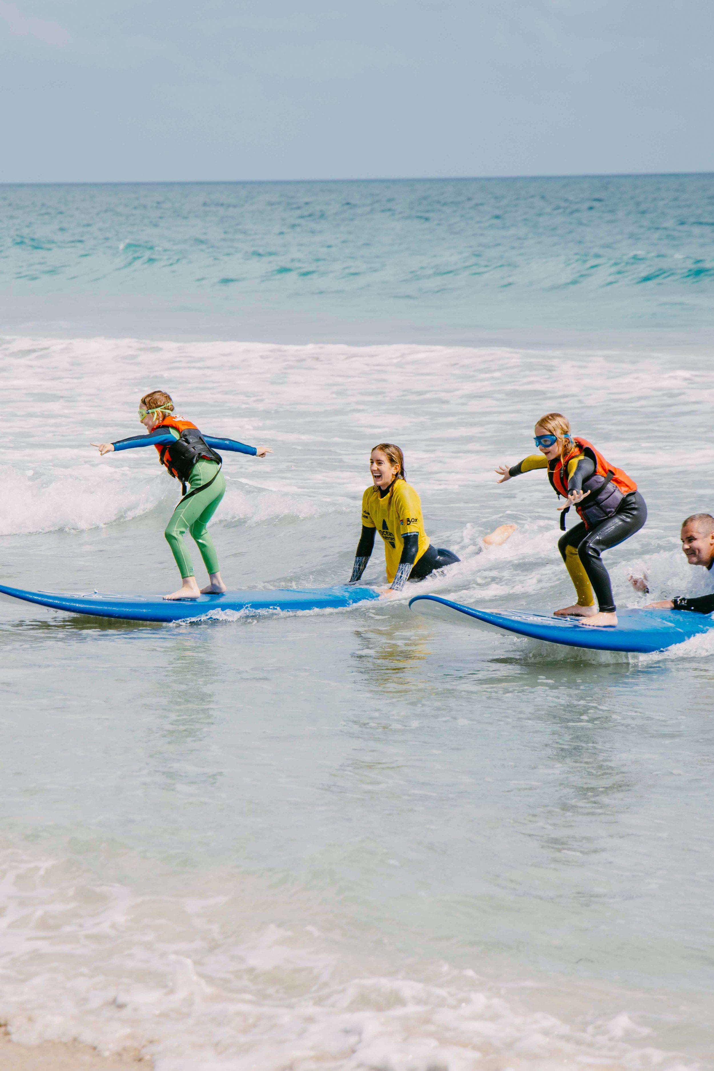 2 surfers with kids on their surfboard