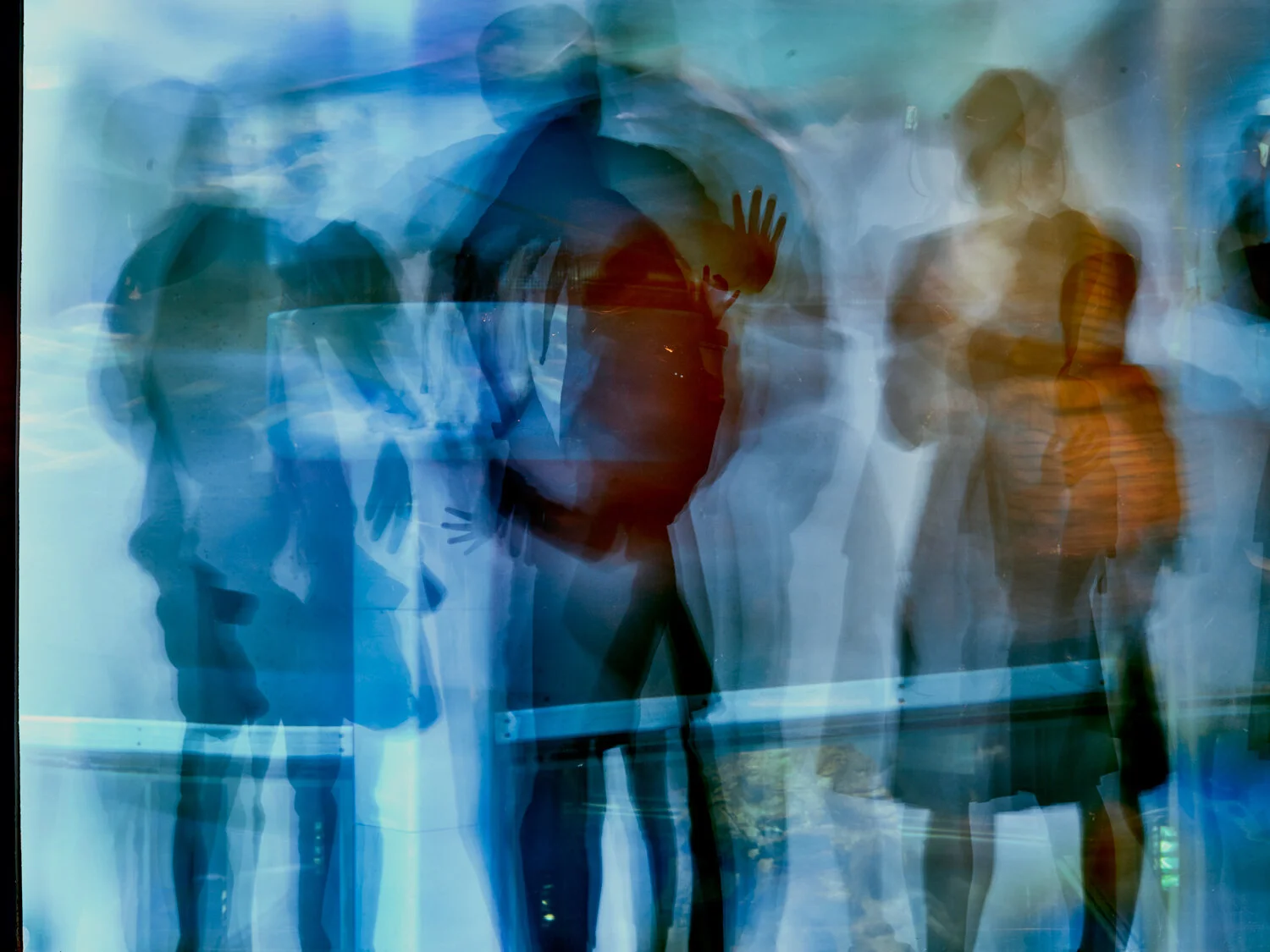 Menschen, die durch eine Glasfassade gehen, wirken verschwommen und reflektieren den Blick durch die Scheibe