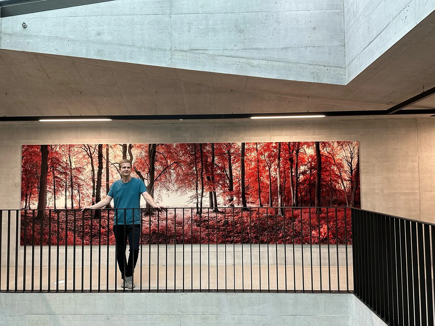 Fotokünstler André Wagner vor seiner großformatigen roten Infrarotfotografie als Kunst-am-Bau-Installation in einem Treppenhaus in Zürich.