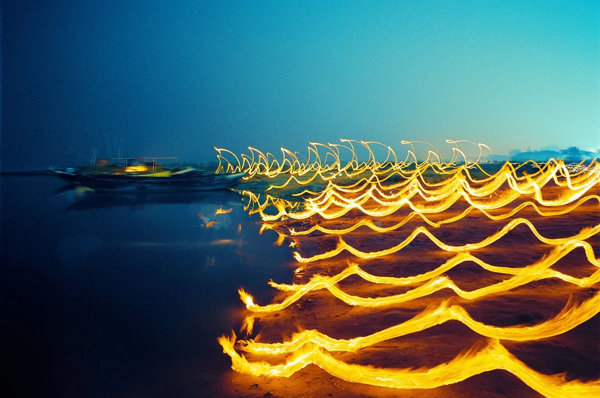 Lichter und Boote am Wasser bei Nacht, durch Light Painting verweht.