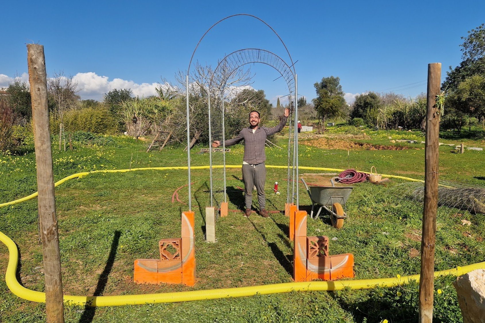 WWOOFer Leonardo setting up an archway for vine growing, on the new Miyawaki Food Forest experiment