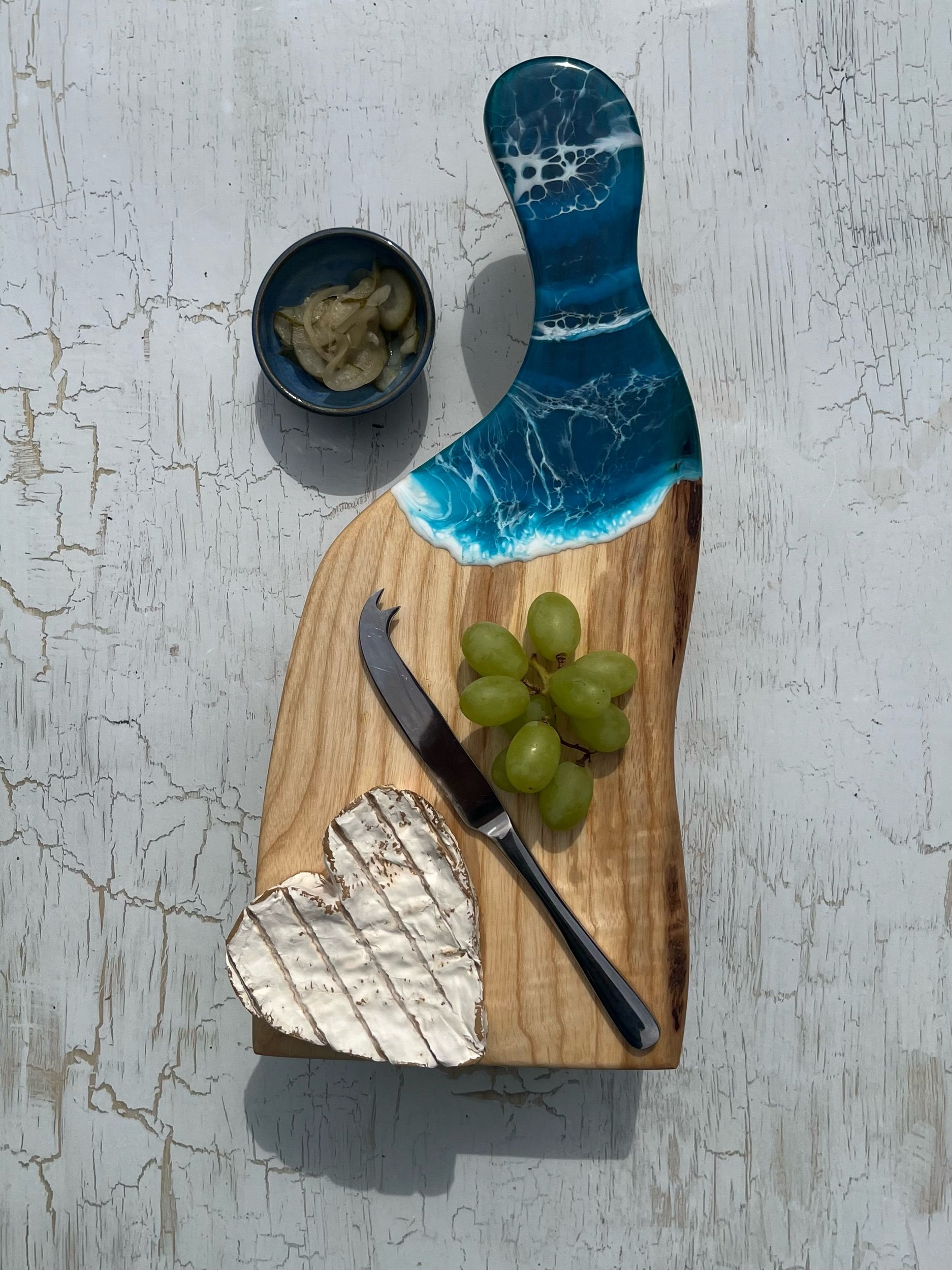 Handcrafted wooden paddle shaped cheese board with ocean inspired resin art