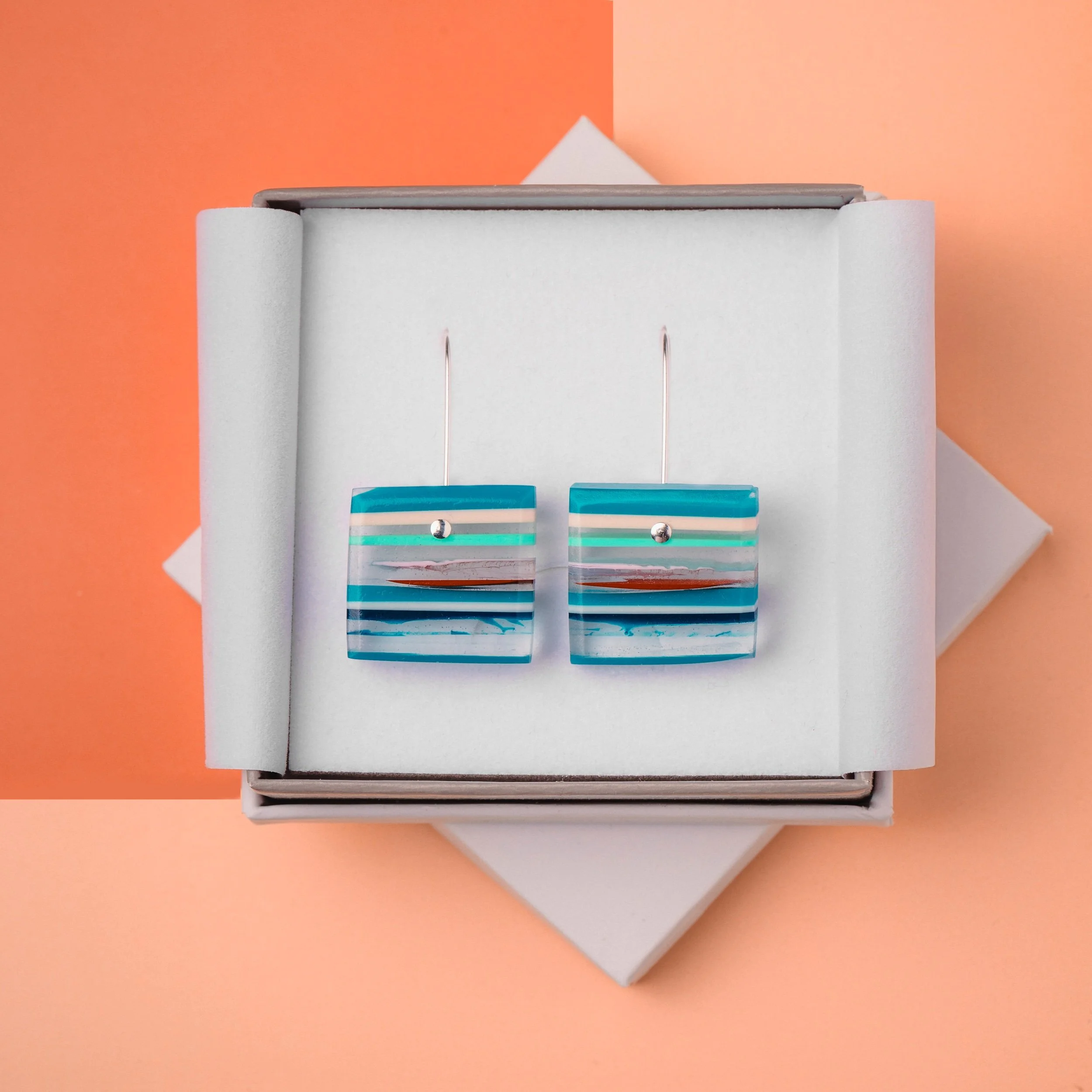 square cut recycled resin dangle earrings with layers of blues, clear and red resin