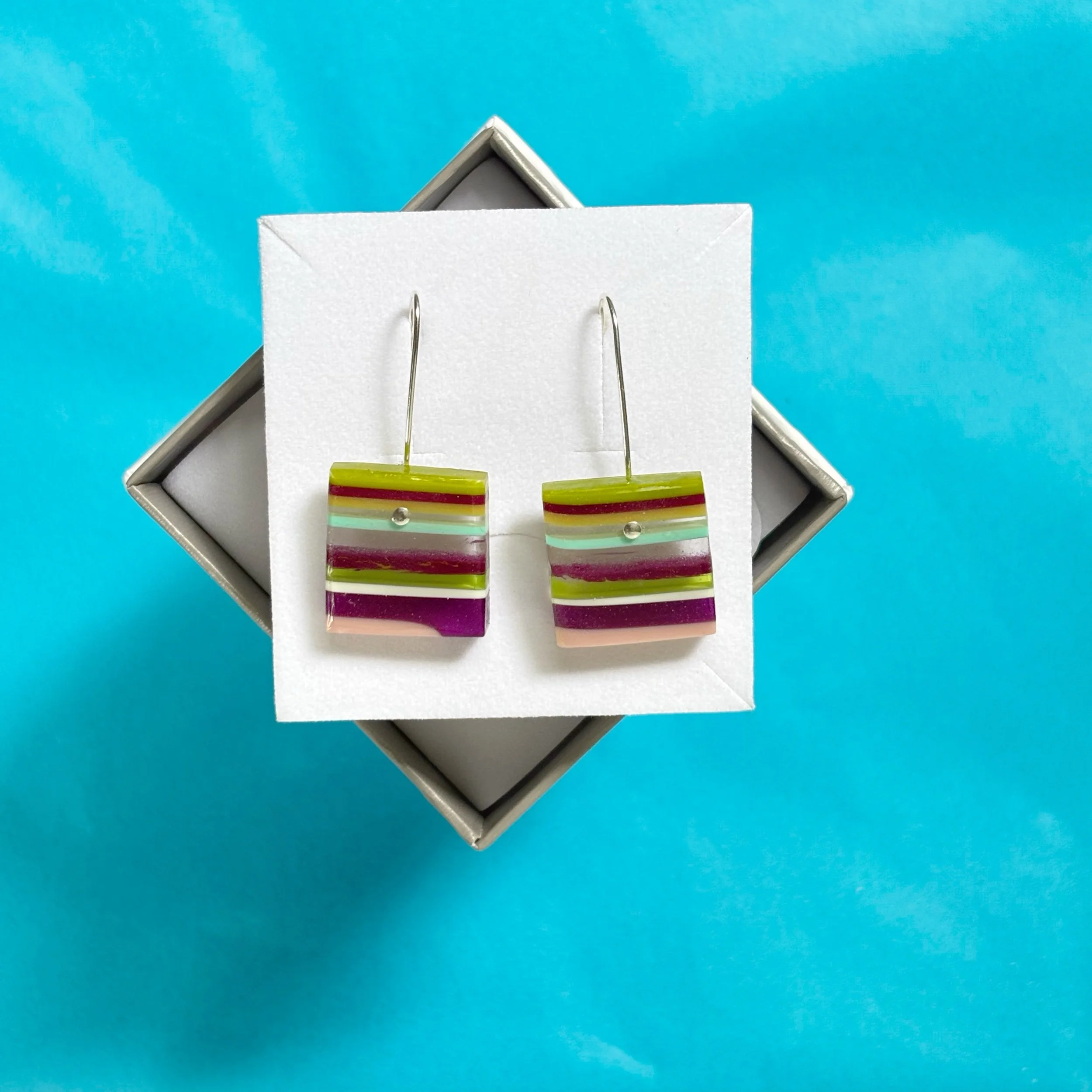 square cut hand made dangle earrings made from recycled resin in shades of purple and green among other colours