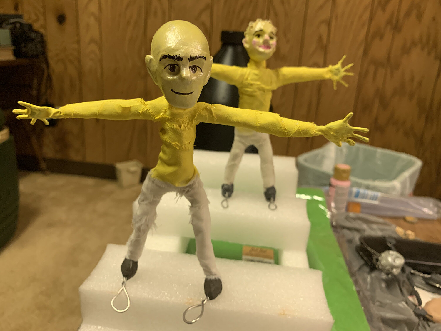  Two characters in yellow shirts and beige pants in claymation. 