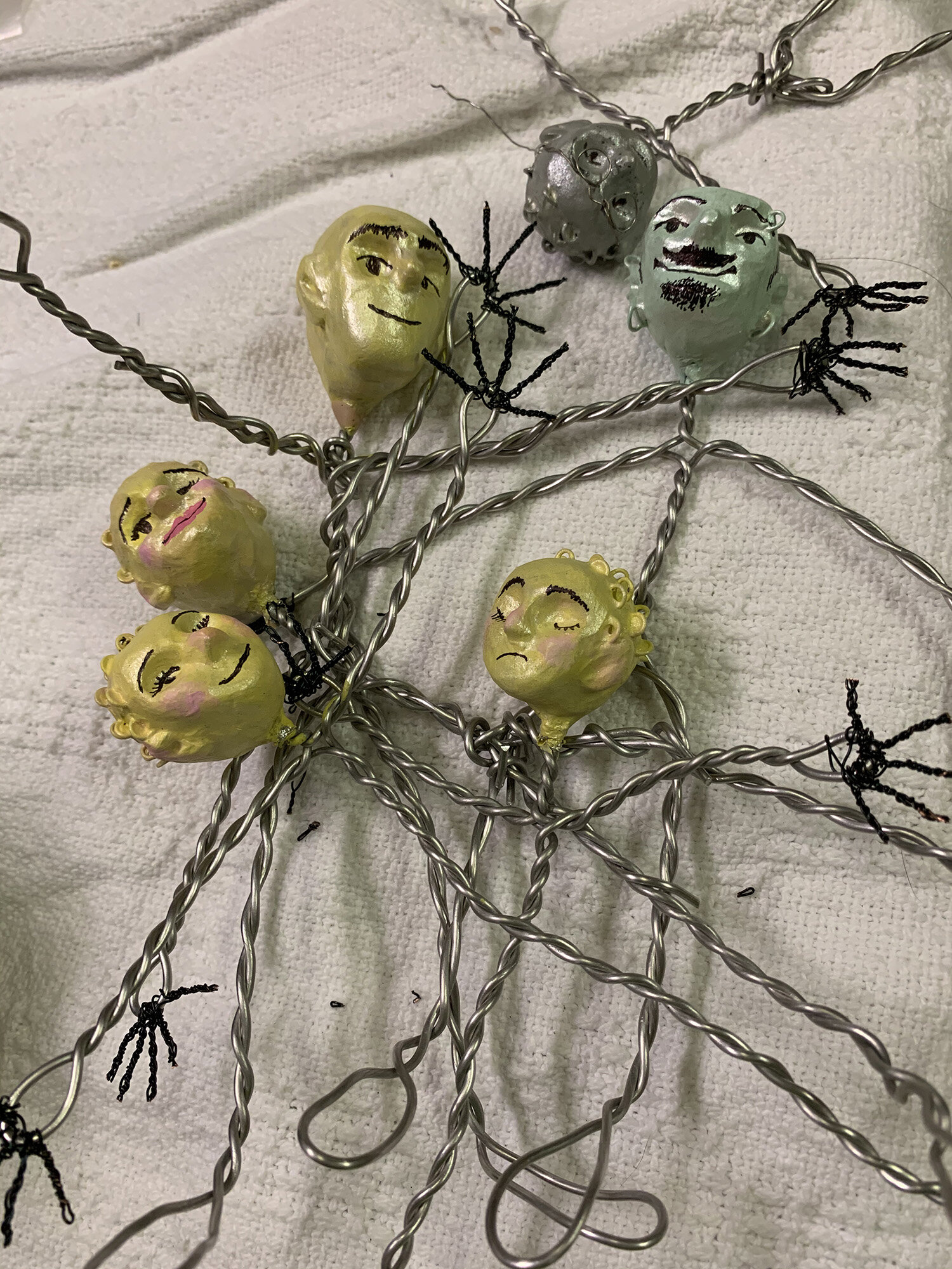  Three clay heads tied together with wire on a white blanket. 