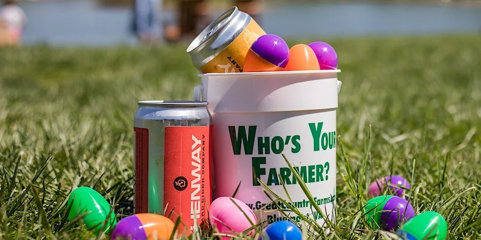 adult easter egg hunt image of a white bucket filled with easter eggs. A Henway Hard Cider crowler is next to the bucket on the grass