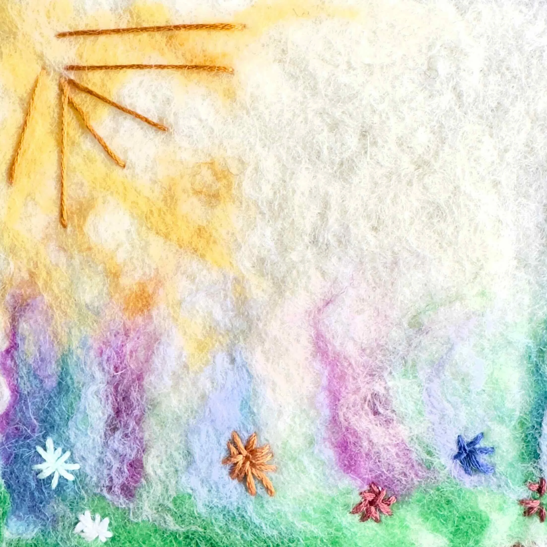Wool painting of a sun and flower made from colorful fibers.