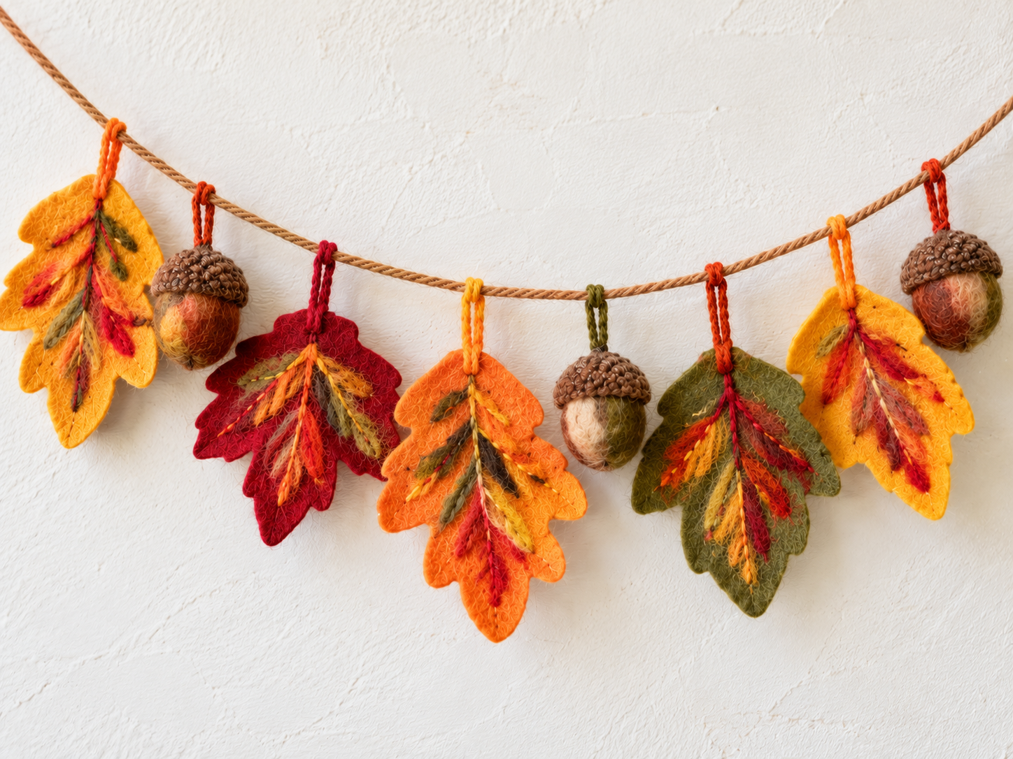 Colorful felt leaves and acorns arranged on a yarn garland.