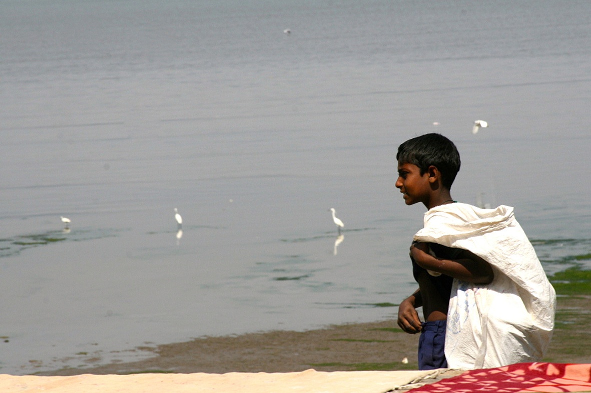 Boy collecting trash along Chowpatty Beach, Mumbai, India