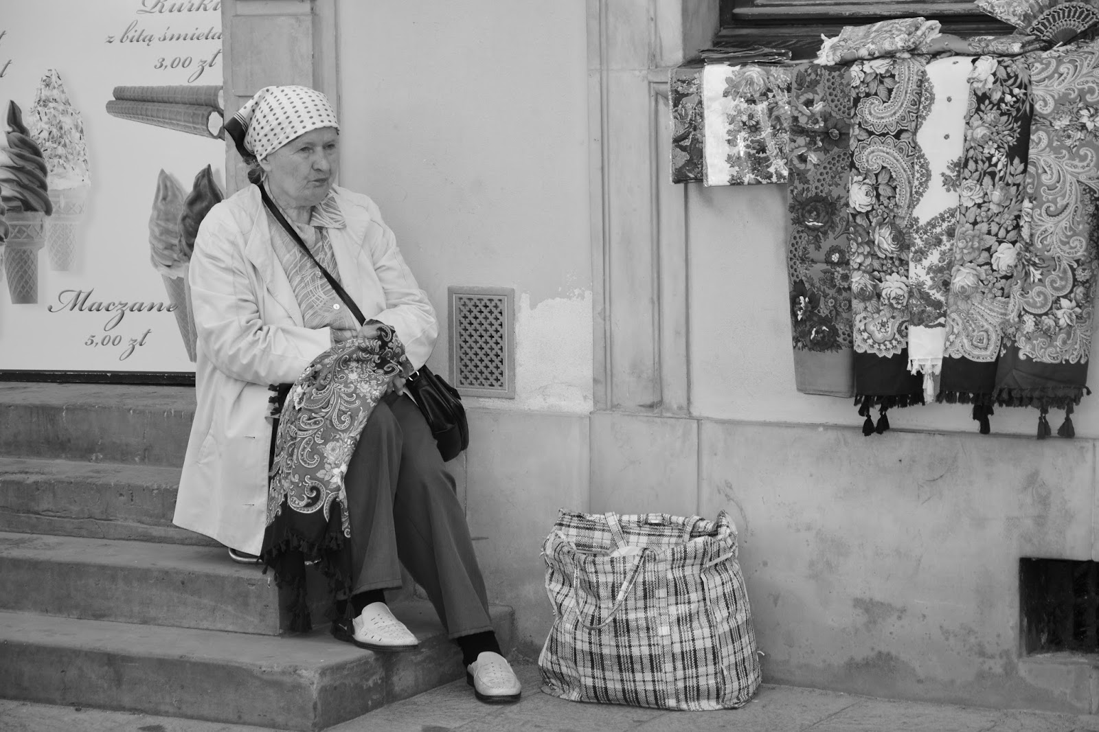 Woman knitting on shop step, Warsaw, Poland