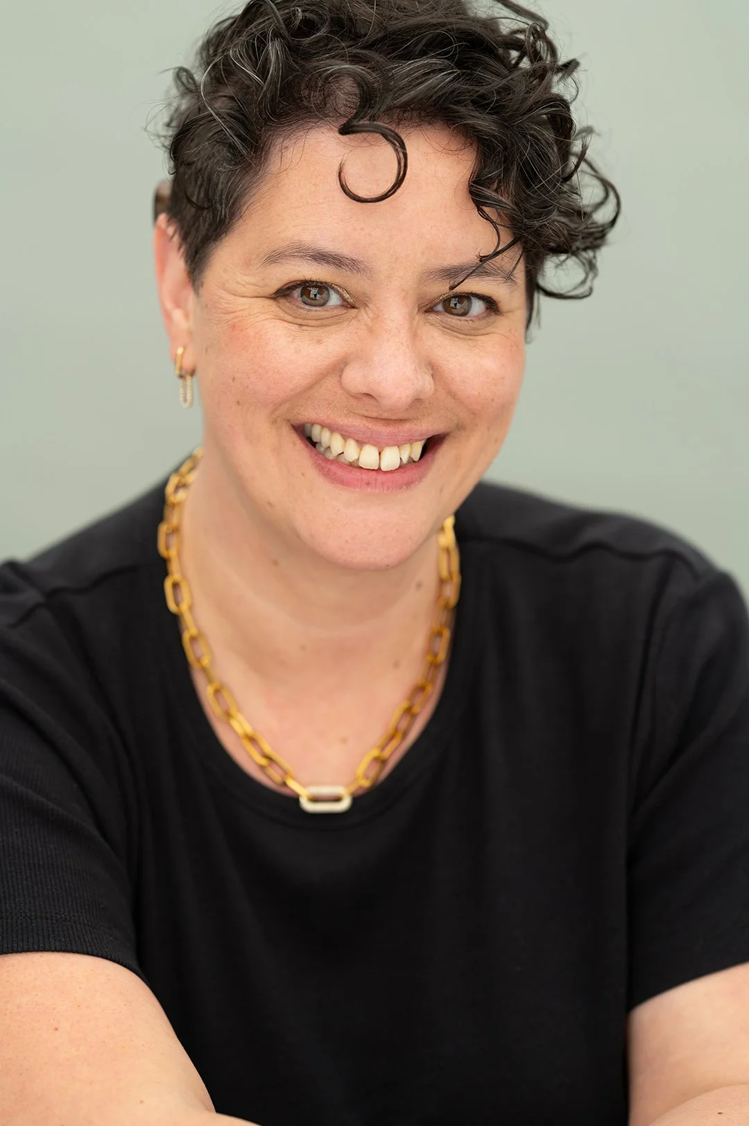 A woman entrepreneur in a black top with short dark hair smiling
