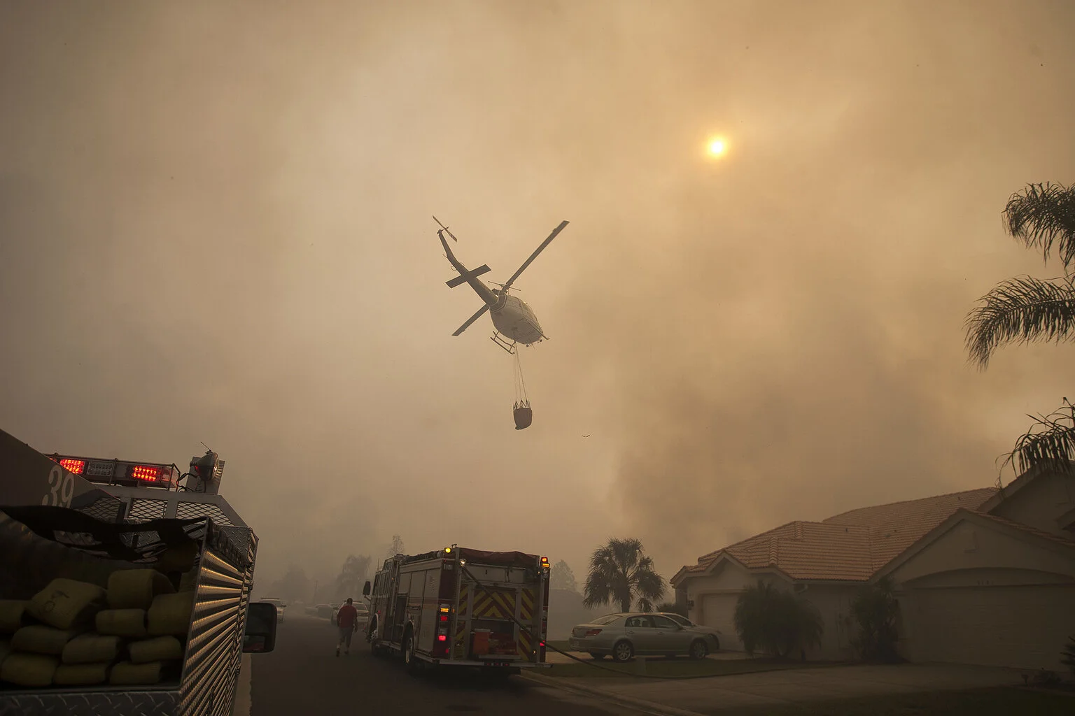  A helicopter flies over homes at Glen Lakes to battle a fire on Friday. Firefighters from five agencies are battling a prescribed burn Friday afternoon that flared out of control in the Chassahowitzka National Wildlife Refuge and threatened homes in