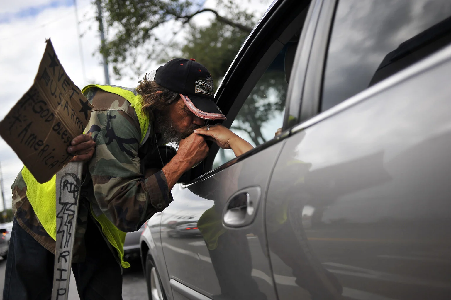  While holding his cane and sign Ronald Burden(cq) of Tampa leans over to kiss a woman's hand that gave him a one dollar bill at the corner of Dale Mabry and West Spruce street on Tuesday, November 1, 2011. "I'm trying to get enough money to survive"