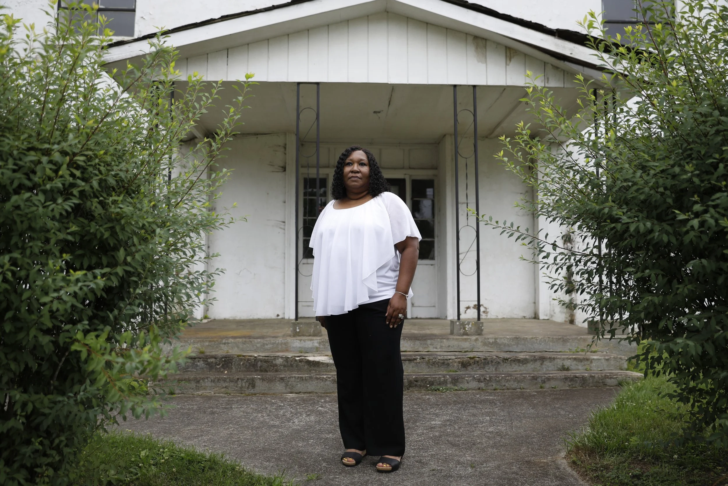 Tina Thomas of Richmond, Virginia, stands outside the former Warren County Jail in Warrenton, North Carolina, where her great-great-grandfather Alfred Williams and Plummer Bullock were jailed before being lynched on January 21, 1921. Days earlier, th