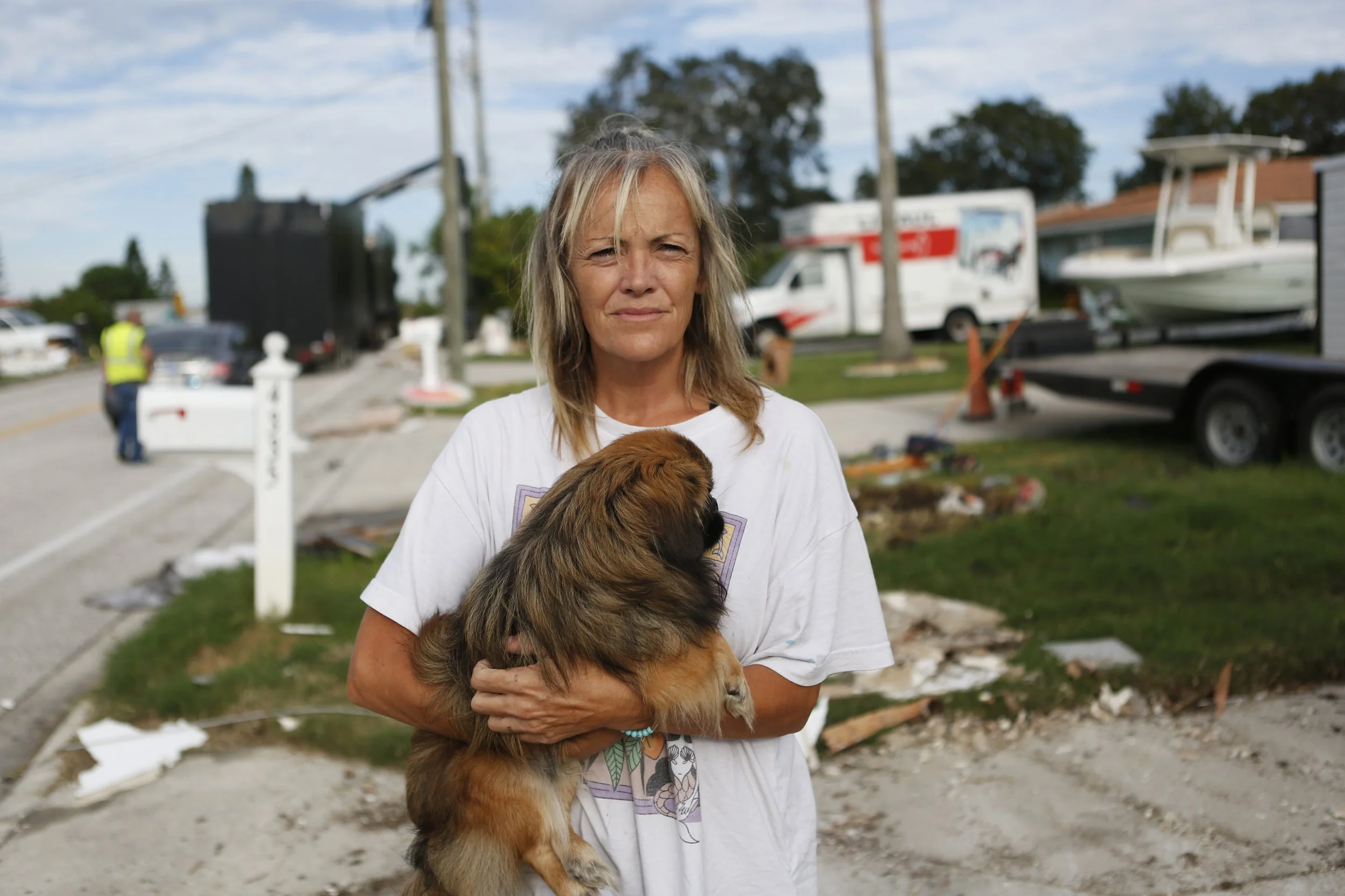After suffering severe flood damage from Hurricane Helene, Sandra White, a resident of New Port Richey, Florida, takes a break with her dog, Buoy, while preparing to evacuate again with her partner ahead of the arrival of Hurricane Milton on October 