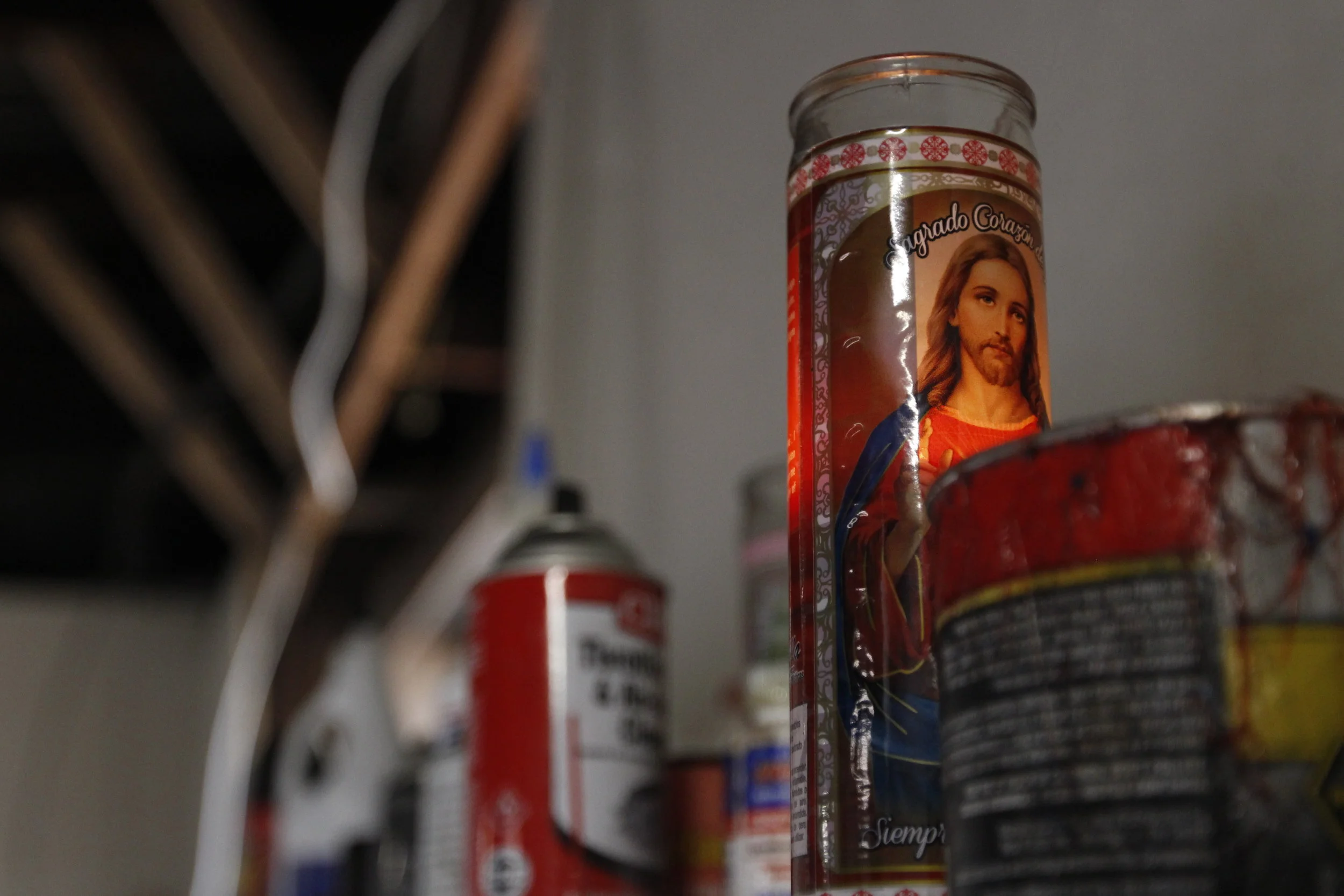  A religious candle sits on a shelf next to motor oil and paint in Aparicio’s Garage in Greensboro, Georgia. The Aparicios are practicing Catholics and have decorated their business with things that, according to Andre, “keep God near.” 