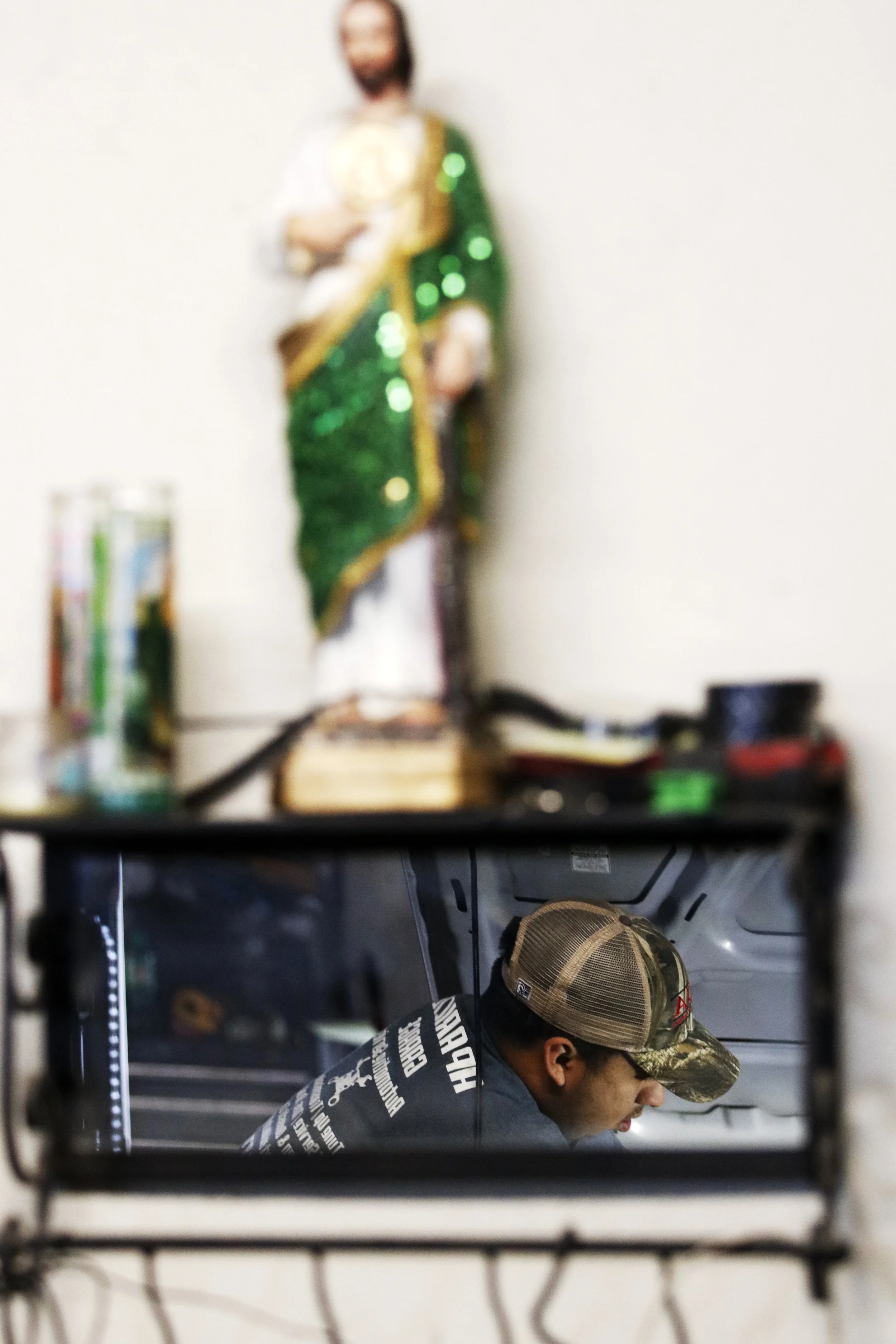  Andre Aparicio works on a vehicle in Aparicio’s Garage in Greensboro, Georgia. The Aparicios are practicing Catholics and have decorated their business with things that, according to Andre, “keep God near.” 