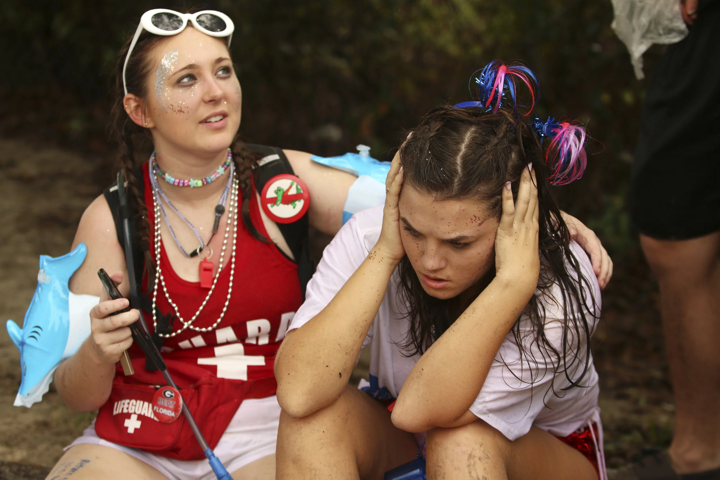  A student, dressed as a lifeguard, helps out a friend as they wait for an uber in the East Beach parking lot. 