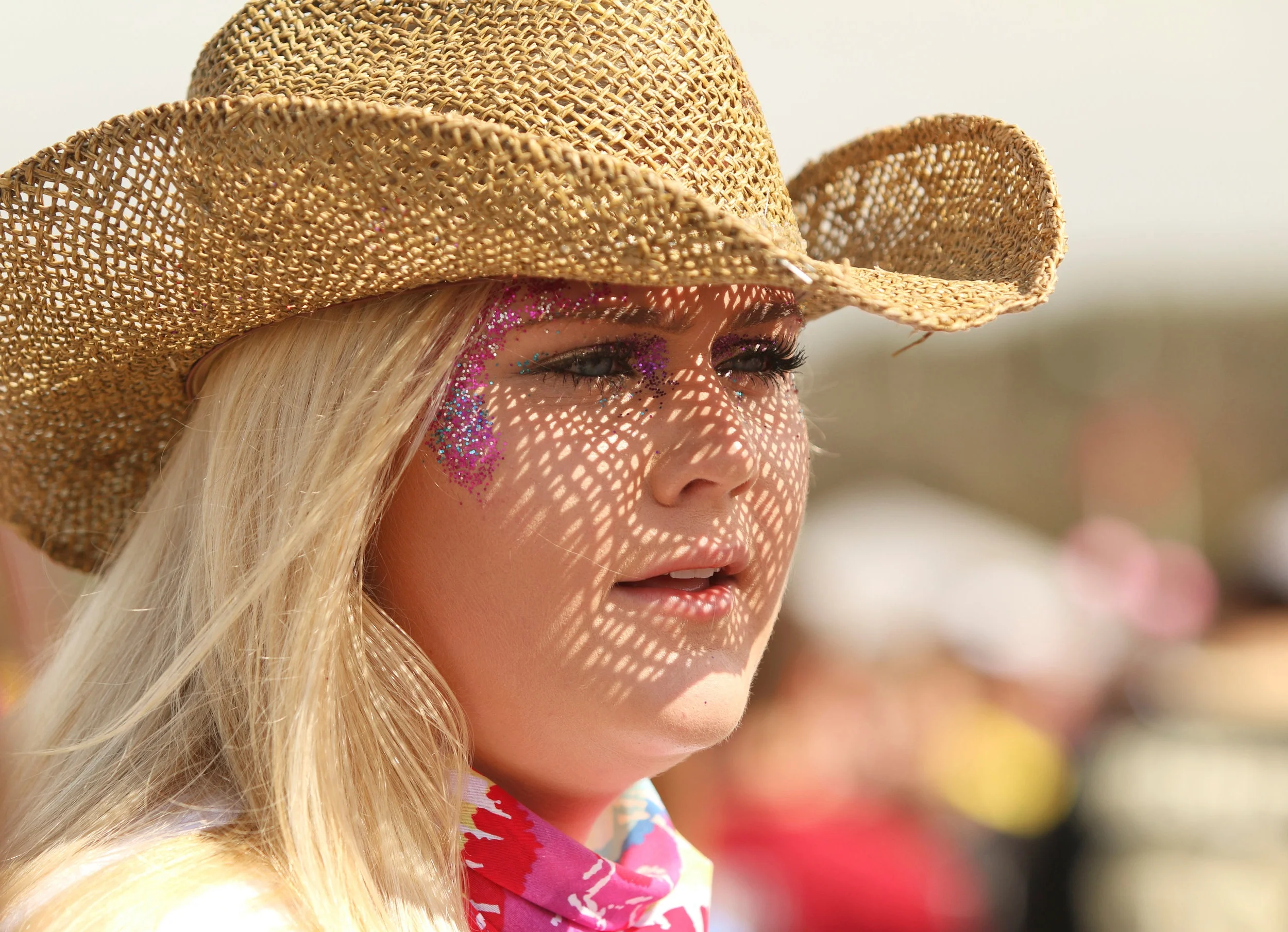  A woman dons a straw cowboy hat and face glitter. 