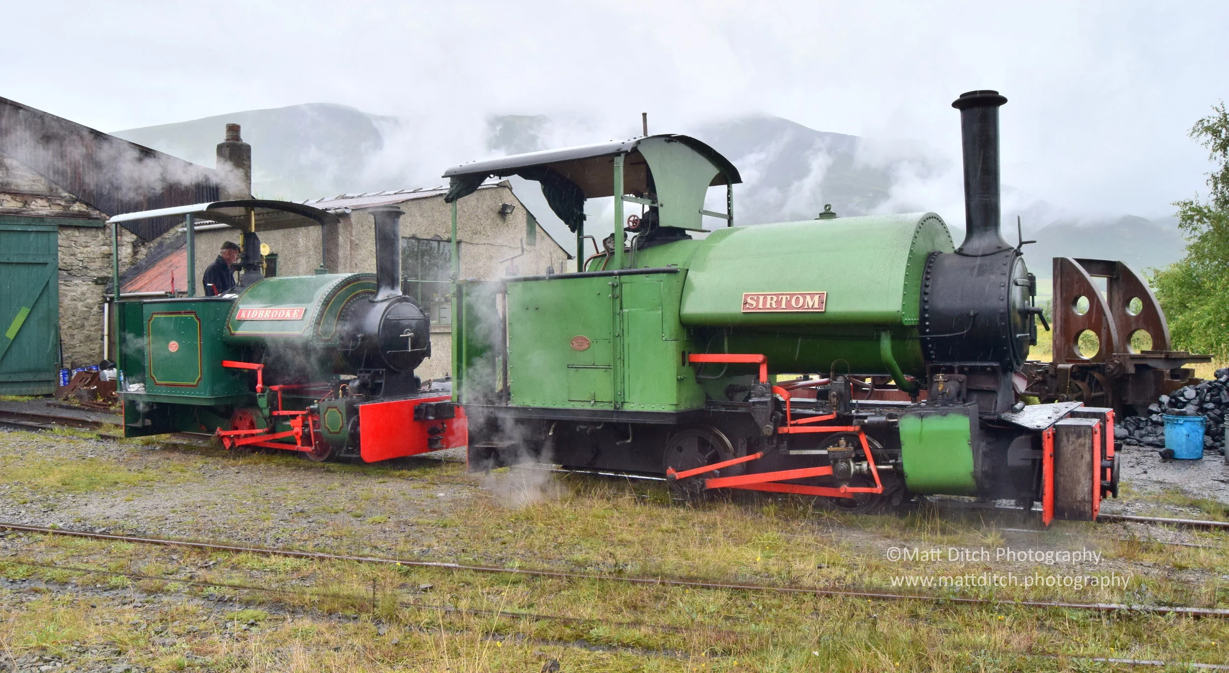  Resident Bagnall 0-4-0ST “Sir Tom” and visiting Bagnall “Kidbrooke” stand outside the engine shed during some typical Cumbrian weather!  