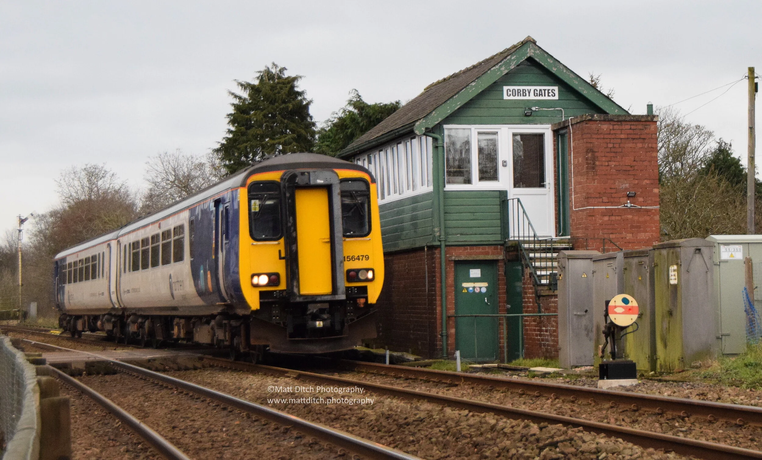 Now moving slightly east from the S&amp;C to the Tyne Valley at Corby Gates near Wetheral. Northern Class 156 No.156 479 passes Corby Gates Signal box with a Newcastle-Carlisle service.   