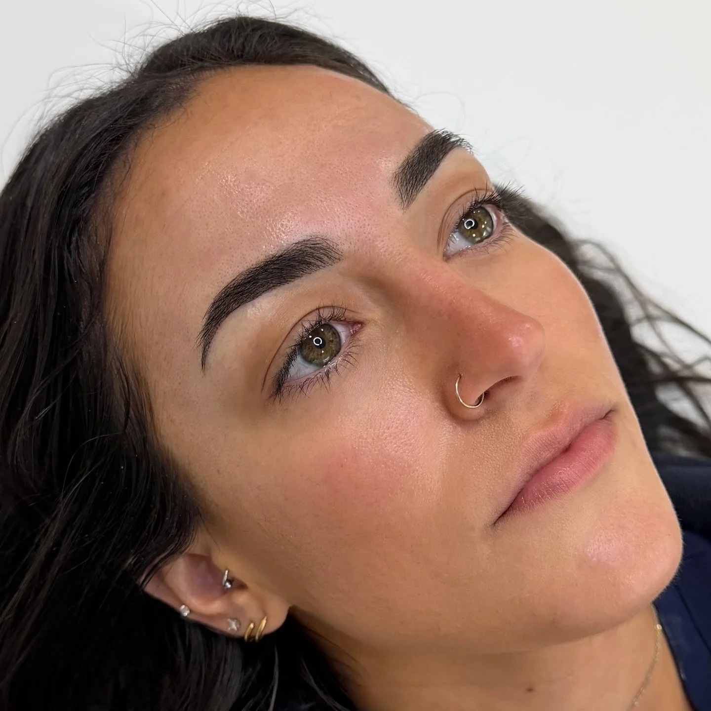 A beautiful freshly touched-up set of brows! We originally did combo brows but the results were a bit underwhelming for how powerful her natural brows are. We needed more!
So we switched to full powder and went slightly larger/darker after seeing how
