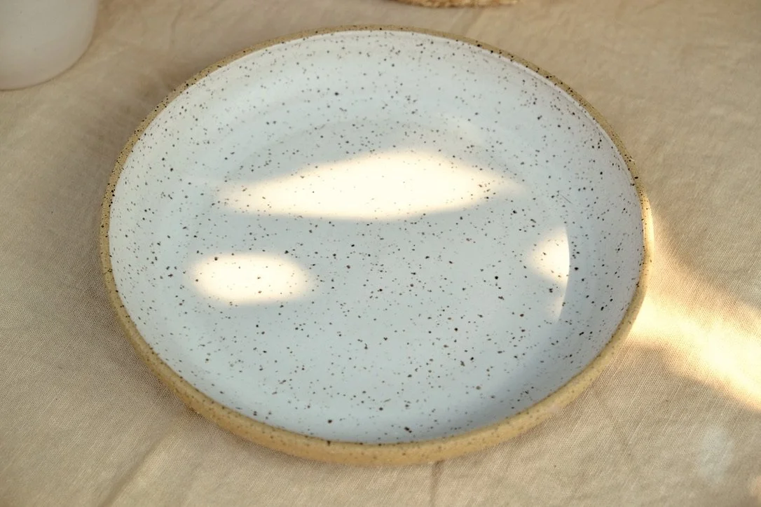 Handmade ceramic wheel-thrown bowl plate, glazed matte white on the inside and left as raw speckled clay on the outside, resting on off-white linen tablecloth. (Copy)