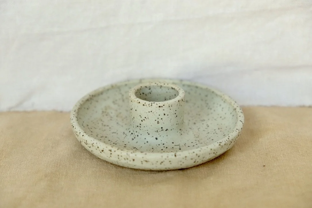 Handmade wheel-thrown mint ceramic candle holder sits on a tan table cloth.