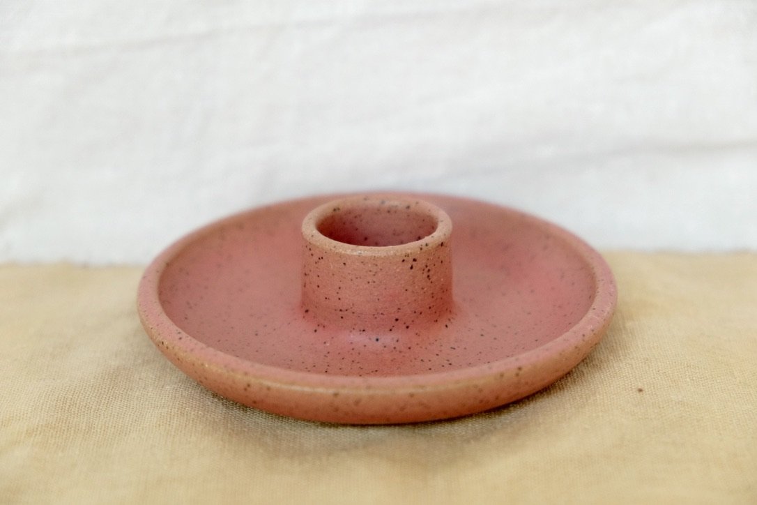 Hand-thrown ceramic avocado watermelon red holder sits on a tan table cloth.
