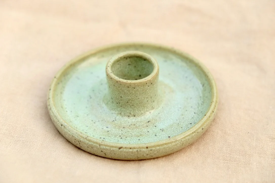 Hand-thrown ceramic melon green candle holder sits on a tan table cloth.