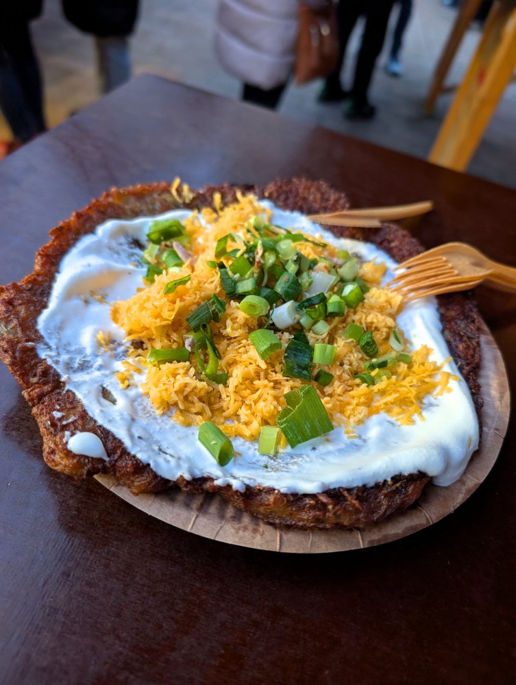 A fried potato cake covered with sour cream, cheese, and green onions
