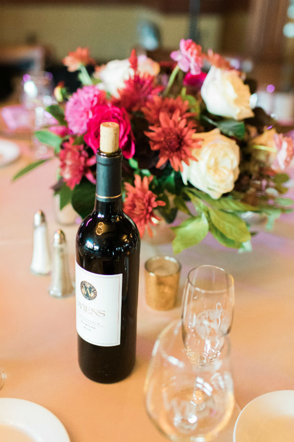 Wine bottle on table with bouquet behind it