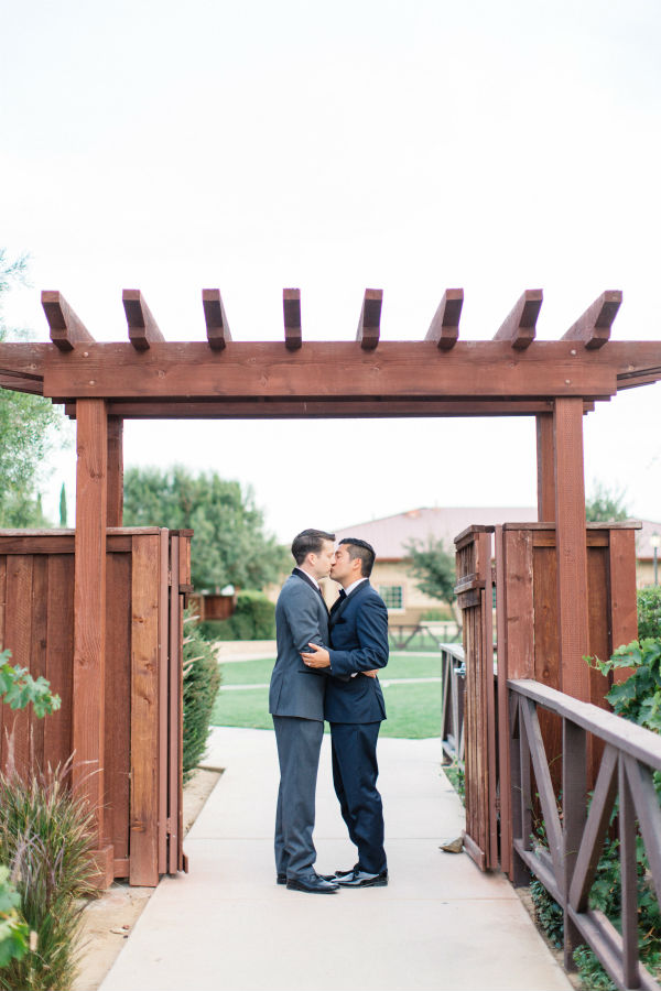 Male couple kissing under gate archway