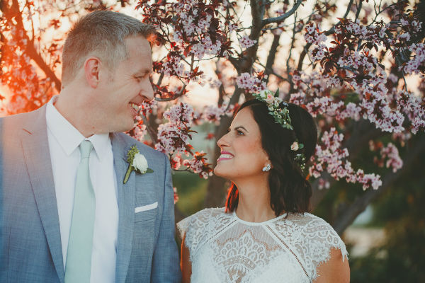 Bride &amp; groom gazing at each other with flowering tree in the background