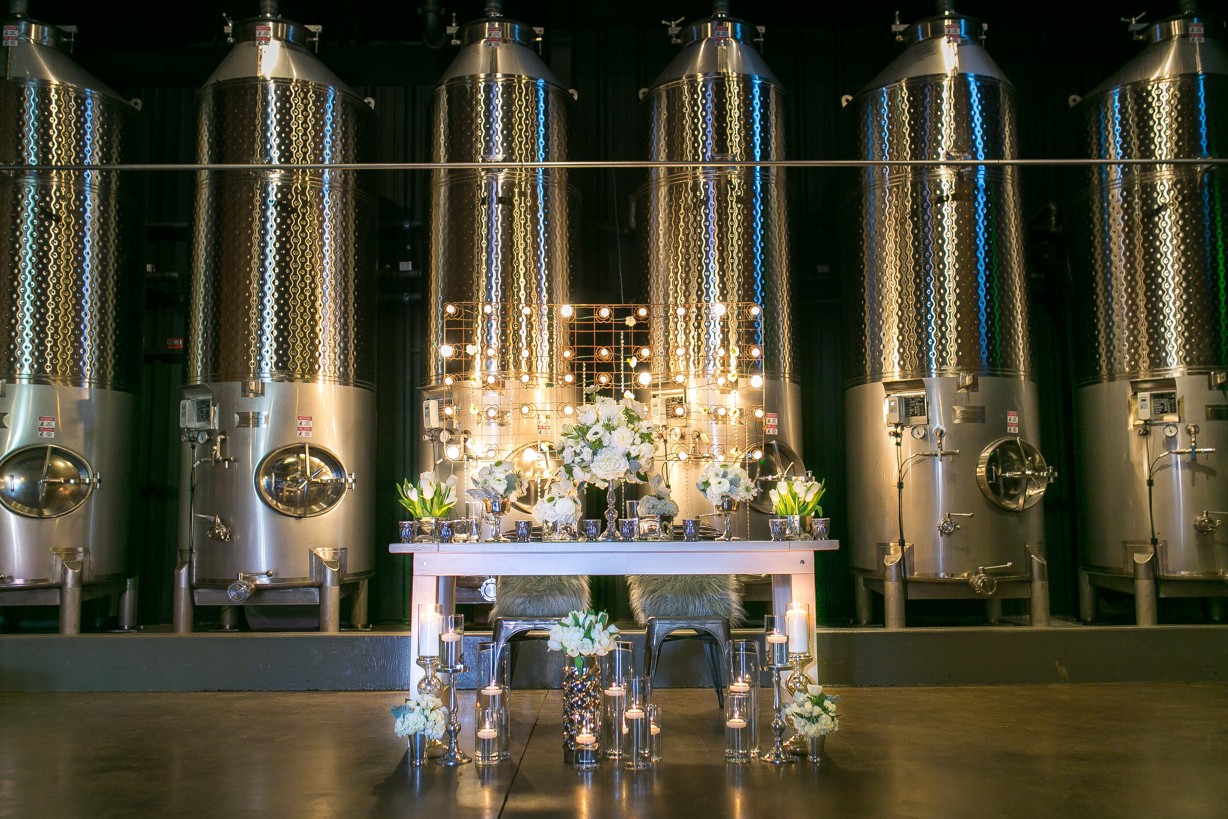 Head table set up in front of metal wine tanks