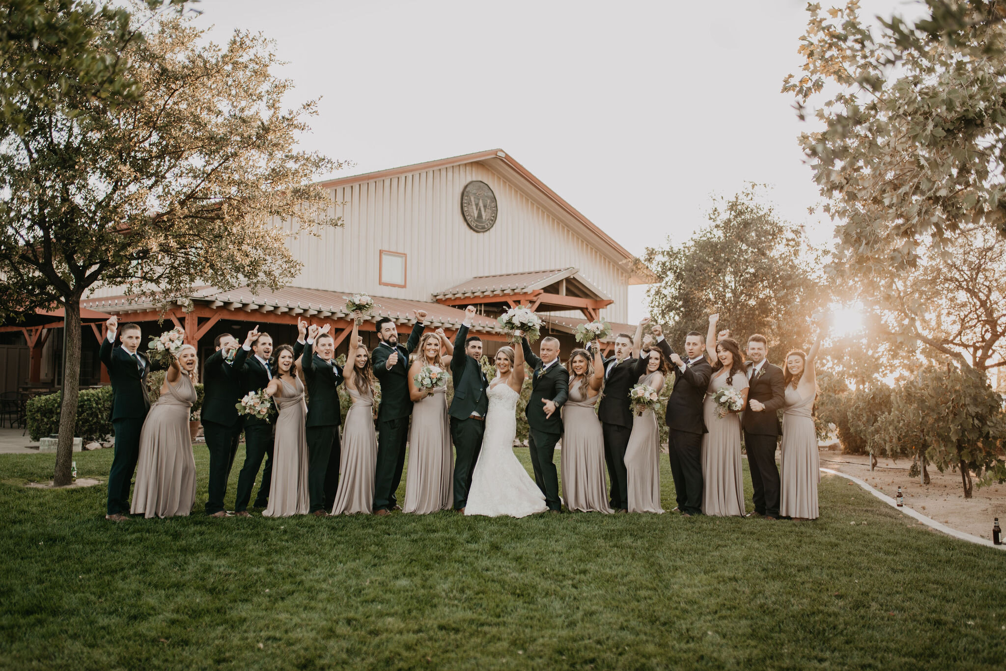 Wedding party posing on grass with Wiens tasting room in background