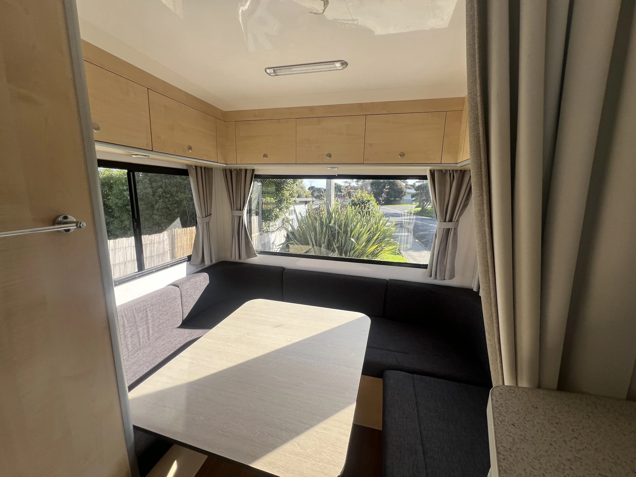 Rear lounge seating in the Leo 6 berth motorhome with wraparound sofa and large windows.