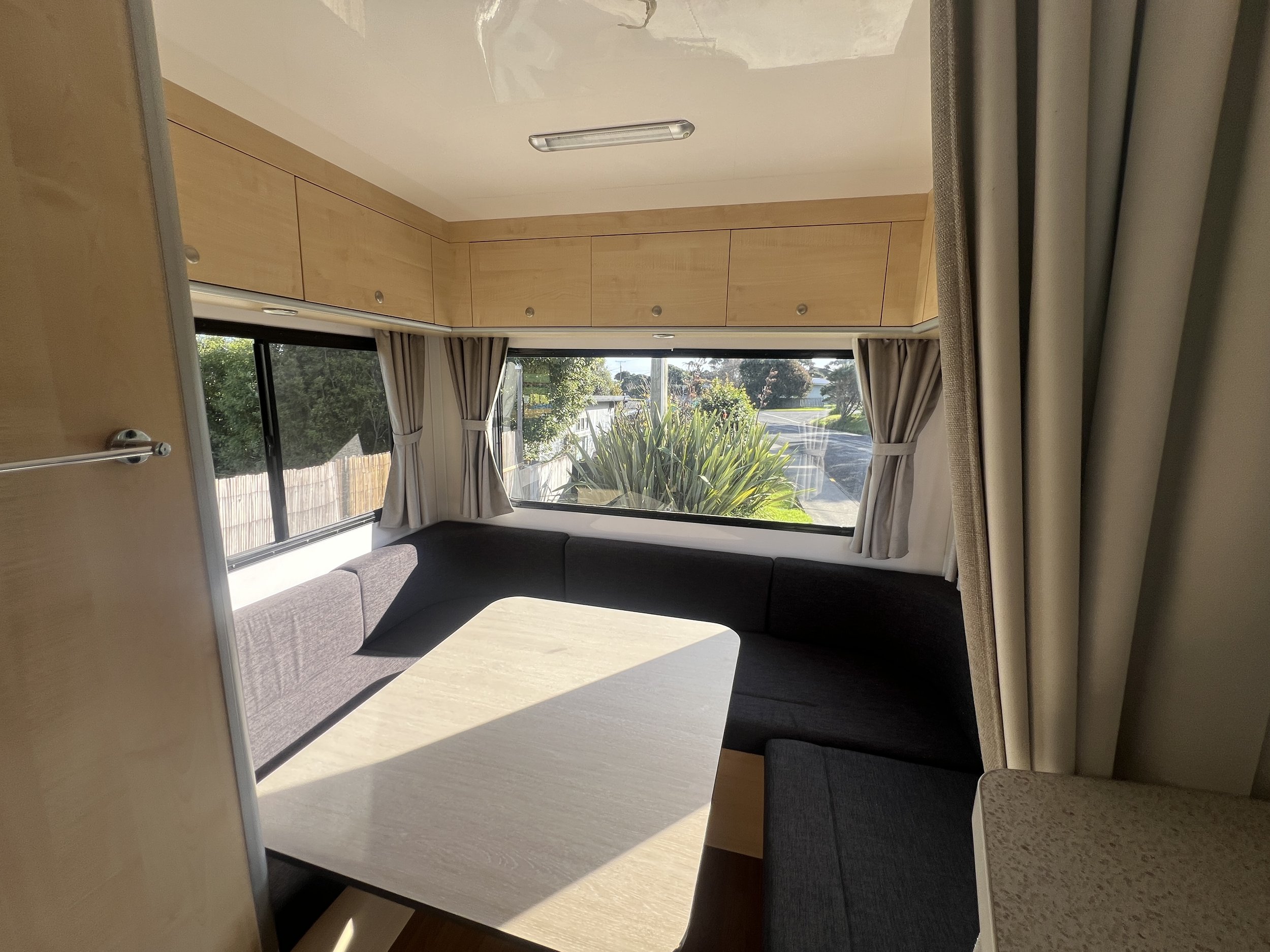 Rear lounge in the Mojo Campers Leo motorhome with wraparound seating and large windows, converts to a double bed