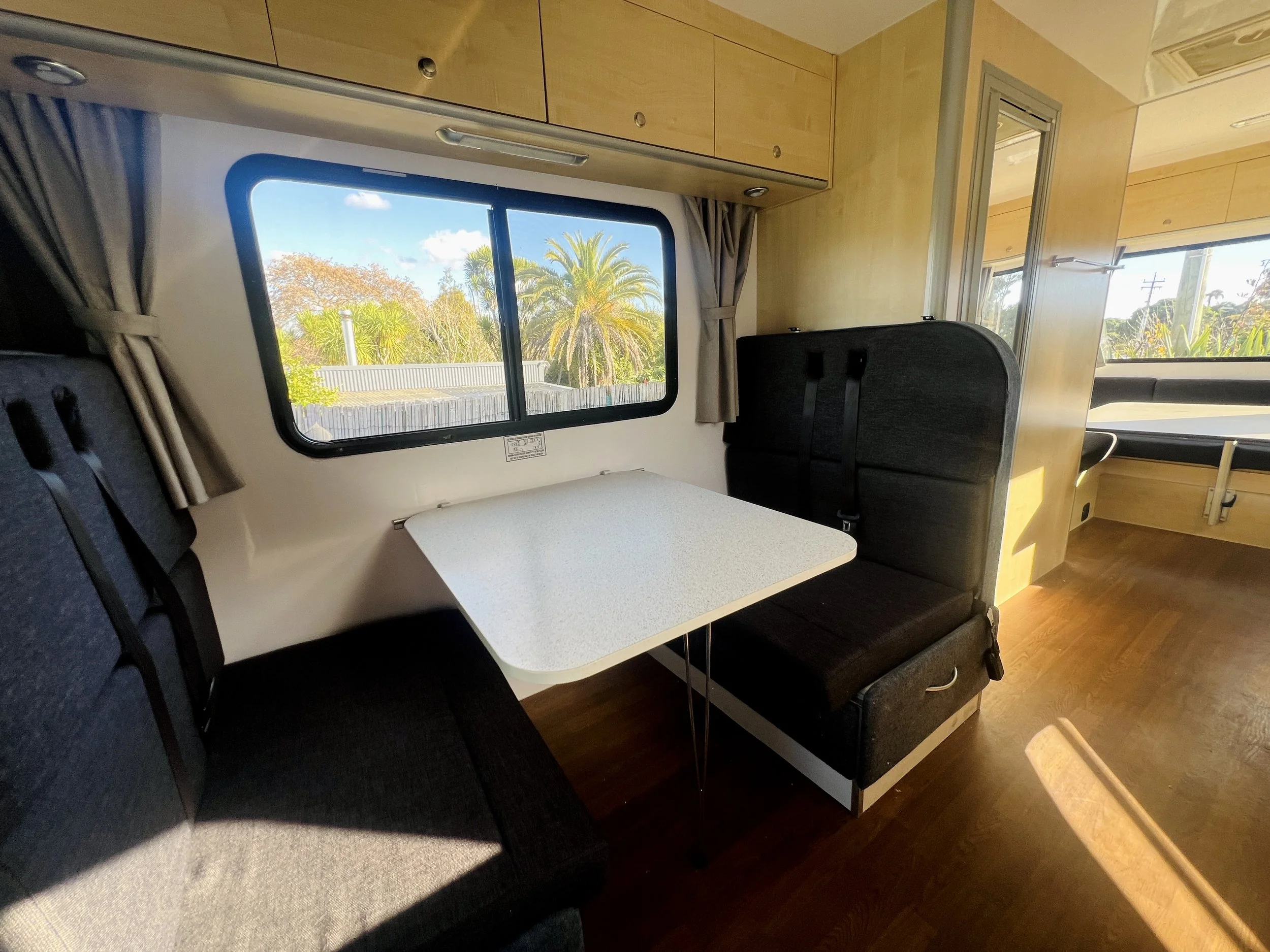 Dinette dining area in the Leo 6 berth motorhome with table set up and a window outlook, converts to a bed
