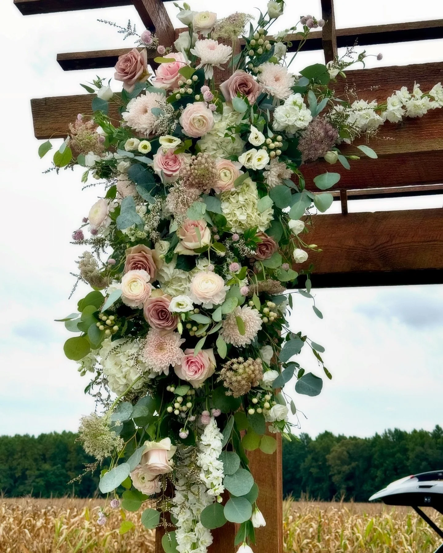 We love this corner of the arbor @hopkinsheartland Honey Bee Barn! So many gorgeous designs have been placed here to celebrate our couples. This design was completed with Amnesia roses, Clooney pink ranunculus, pink Mondial roses, lisianthus, gomphre