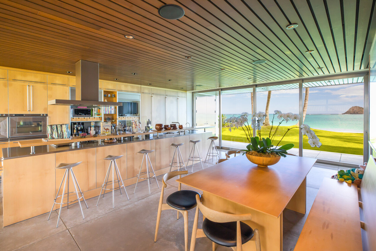    The kitchen features Bulthaup cabinetry in a bleached oak finish,  Gaggenau and Miele appliances, and stainless steel countertops.The bar  is lined with Jamaica Stools by Pepe Cortes for Knoll, and Hans Wegner  elbow chairs in bleached oak surroun