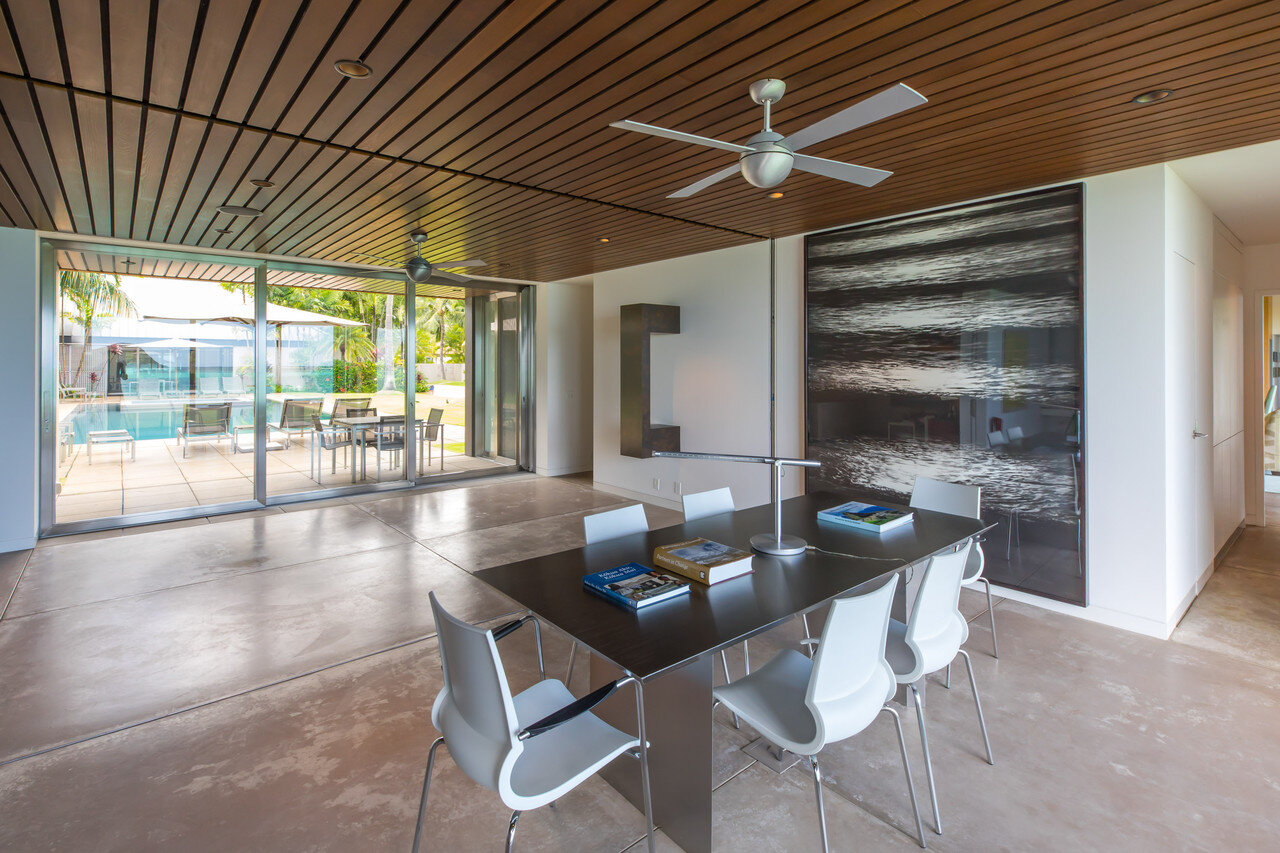    In the main house, a charcoal artwork of waves by Robert Longo hangs by a  custom table made of metal laminate, produced by Seamus Fairtlough of  Restored by Fairtlough. Chairs are Gigi stacking chairs by Marco Maran  for Knoll. A slot in the wood