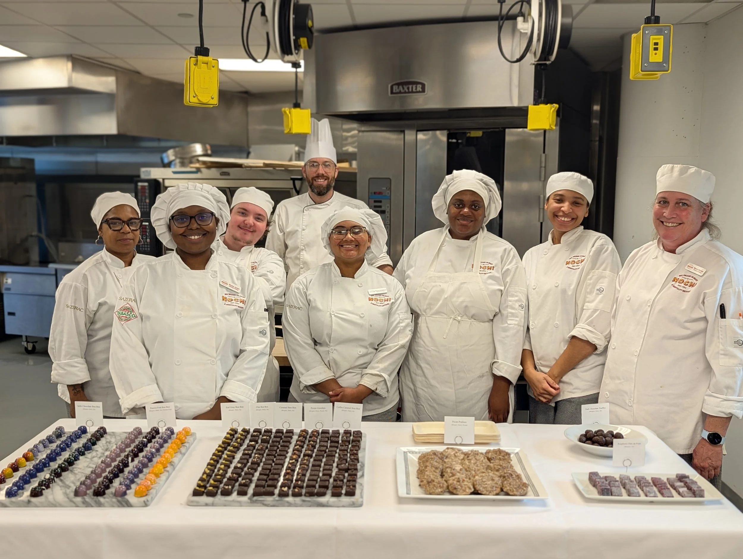Baking & pastry arts students and instructor posing behind chocolate showcase
