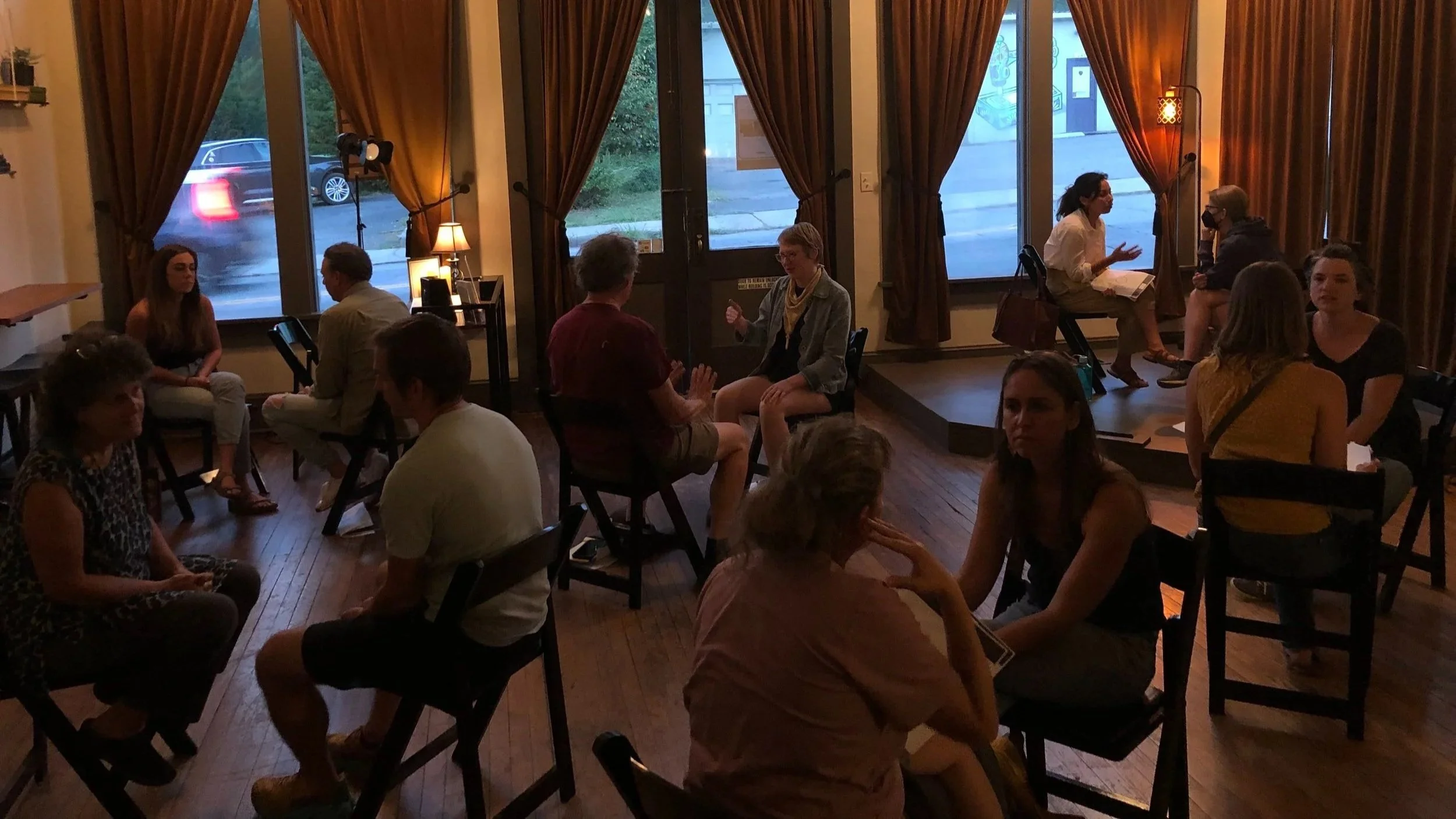 People in groups of two sit in chairs facing each other while having conversations.