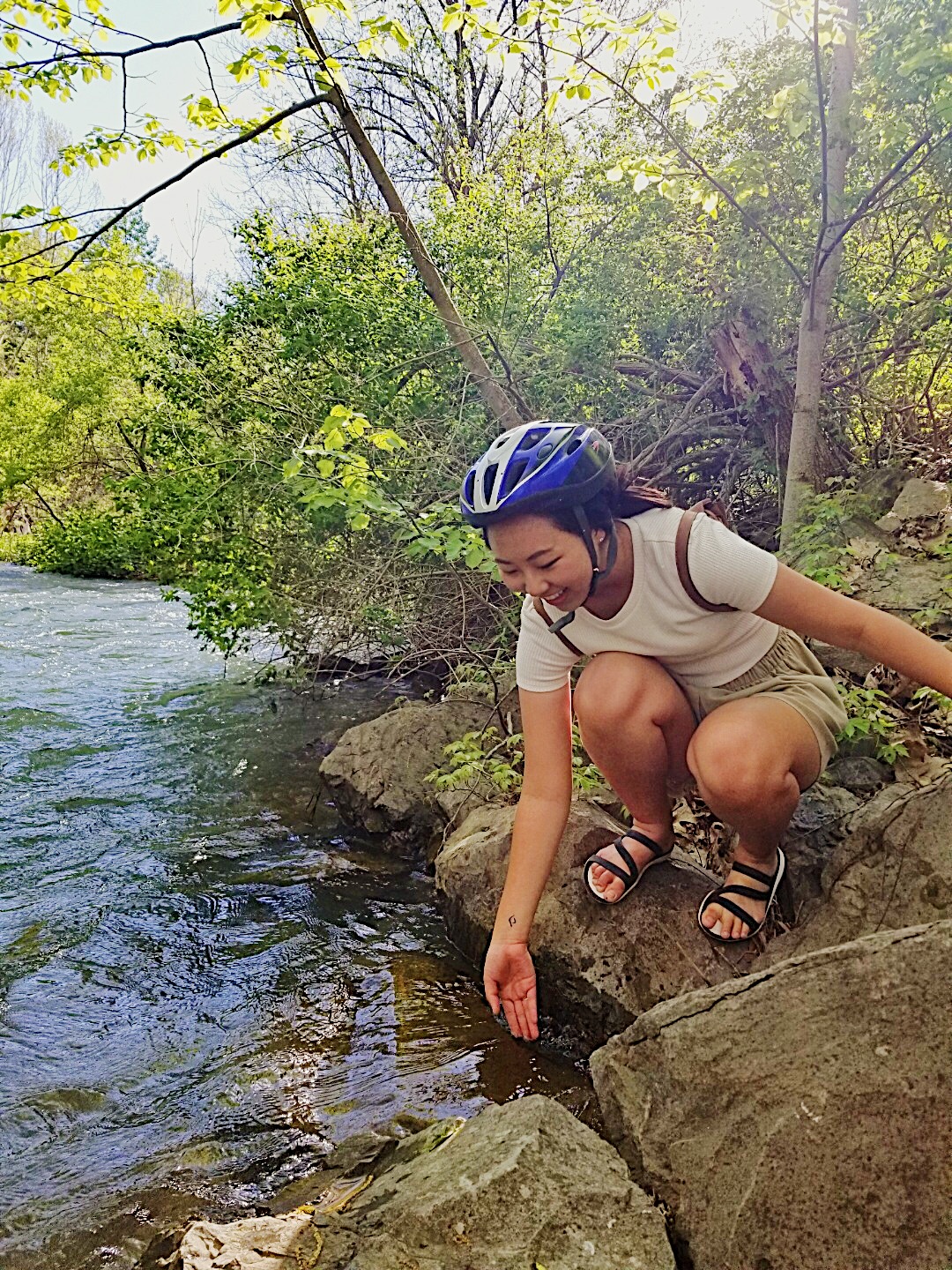 Michelle squatting by a lake with bike helmet..JPG