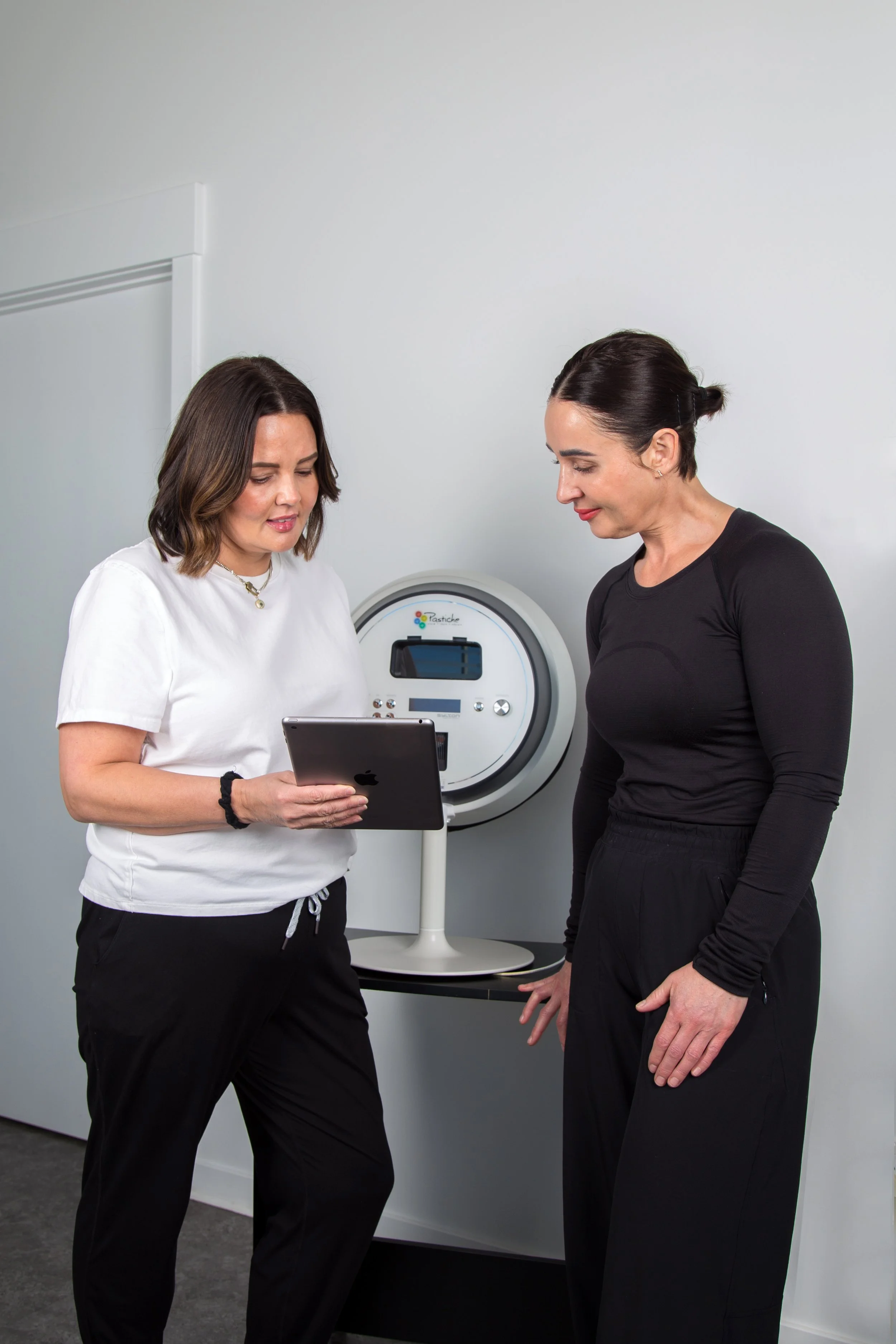 Two women use skin analysis machine to detemine next steps for client in Warman Saskatchewan who may need microneedling