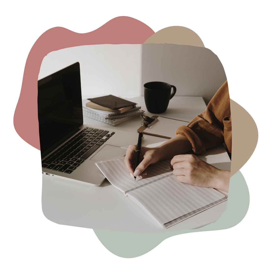 Eine Person schreibt in ein Notizbuch auf einem Schreibtisch mit einem Laptop, einer schwarzen Tasse und mehreren Notizbüchern.
