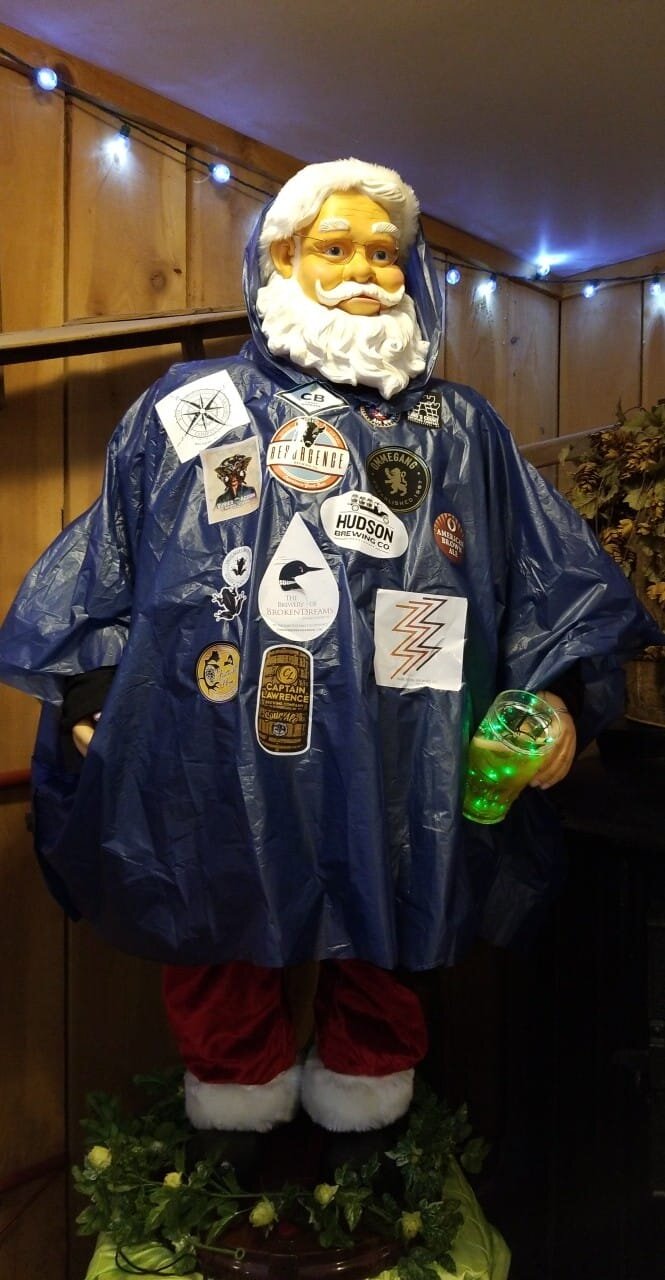 Animated Santa figure wearing poncho covered with New York State brewery stickers