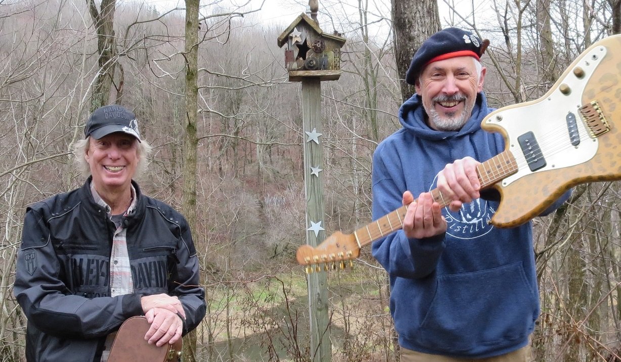 Dave Barker and Steve Blaise holding guitars in woods